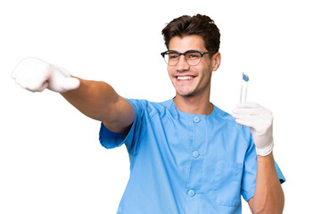 Wall Mural - Young dentist man holding tools over isolated background giving a thumbs up gesture