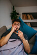 © La Famiglia - An ill young man at home feeling sick and exhausted. A drunk male lying covered on the sofa feeling hungover after last night party.