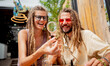 © romaset - Hippie style couple examines under a magnifying glass the joints and buds of medical marijuana