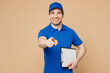 © ViDi Studio - Delivery guy employee man wear blue cap t-shirt uniform workwear work as dealer courier hold clipboard with papers document point index finger camera on you isolated on plain light beige background.
