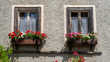 Traditional Flowered Window At The Alps And Dolomites. Colorful Flowers Of A Windows Of A Traditional House. Summer Time. Mix Of Flowers And Colors. General Contest Of The European Alps