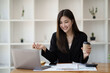 © Parichat - Happy Asian businesswoman working for her project and drinking coffee cup while working, sitting at the office desk.
