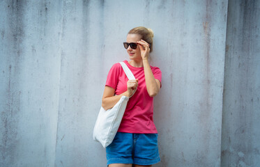 Wall Mural - Female model wearing pink blank t-shirt on the background of an gray wall.