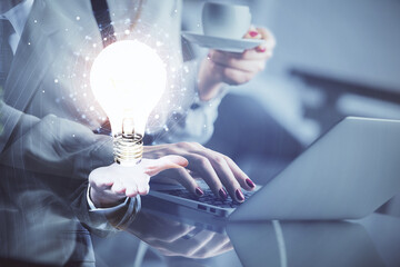Double exposure of woman hands typing on computer and light bulb drawing. Idea concept.