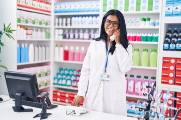 Wall Mural - Middle age hispanic woman pharmacist talking on telephone using computer at pharmacy