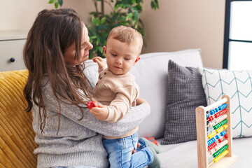 Mother and son playing with abacus hugging each other at home