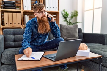 Canvas Print - Young redhead man psychology having teleconsultation talking on the smarpthone at clinic