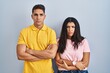 © Krakenimages.com - Young couple standing over isolated background skeptic and nervous, disapproving expression on face with crossed arms. negative person.
