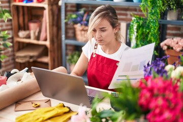 Wall Mural - Young blonde woman florist using laptop reading document at florist