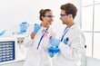 © Krakenimages.com - Man and woman wearing scientist uniform using pipette and test tube working at laboratory