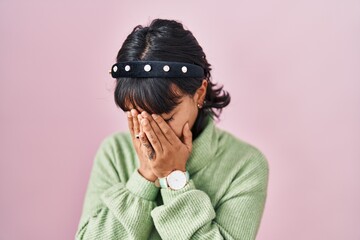 Sticker - Young beautiful woman standing over pink background with sad expression covering face with hands while crying. depression concept.