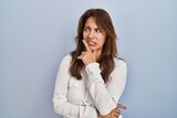 Fototapeta Konie - Hispanic woman standing over isolated background thinking worried about a question, concerned and nervous with hand on chin