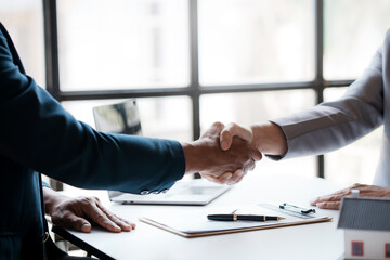 real estate agent shakes hands with a client to sign a home purchase contract congratulating the cli