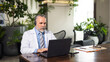 © NVB Stocker - Senior caucasian doctor online video call conference consult patient with headset on laptop computer. Doctor online consultation and telehealth medicine