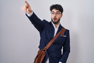 Poster - Hispanic man with beard wearing business clothes pointing with finger surprised ahead, open mouth amazed expression, something on the front