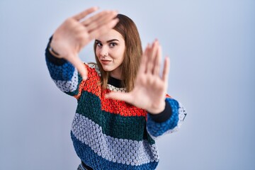 Sticker - Young hispanic girl standing over blue background doing frame using hands palms and fingers, camera perspective