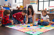 © Krakenimages.com - Teacher with group of boys playing with maths puzzle game sitting on floor at kindergarten
