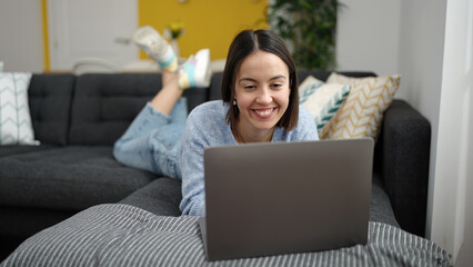 Sticker - Young beautiful hispanic woman using laptop lying on sofa at home