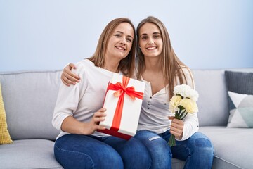 Canvas Print - Two women mother and daughter surprise with birthday gift and flowers at home