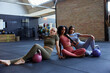 © Flamingo Images - Group of fit women sitting with weights in a gym looking cool