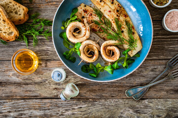 Marinated herring fillets with dill on wooden table
