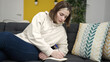 © Krakenimages.com - Young blonde woman writing on notebook sitting on sofa at home