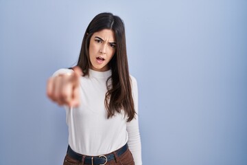 Poster - Young brunette woman standing over blue background pointing displeased and frustrated to the camera, angry and furious with you