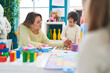 © Krakenimages.com - Teacher and toddler playing with maths puzzle game sitting on table at kindergarten