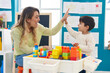 © Krakenimages.com - Teacher and toddler playing with construction blocks high five at kindergarten