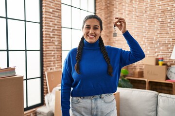 Wall Mural - Young hispanic woman smiling confident holding key of new house at new home