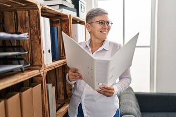 Poster - Middle age woman psychologist reading binder standing at pyschology center