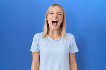 Canvas Print - Young caucasian woman wearing casual blue t shirt angry and mad screaming frustrated and furious, shouting with anger. rage and aggressive concept.