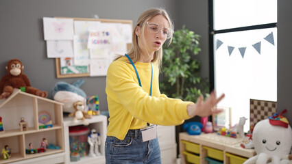 Poster - Young blonde woman preschool teacher asking for silence at kindergarten