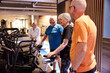 © Flamingo Images - Smiling seniors preparing for a stationary bike class. Group of people in gym. Seniors exercising