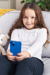 Sticker - Adorable hispanic girl make selfie by smartphone sitting on sofa at home