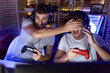 Two hispanic men streamers playing video game covering eyes cheating at gaming room