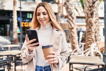 Poster - Young blonde woman using smartphone drinking coffee at coffee shop terrace