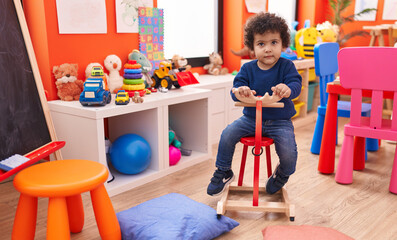 Sticker - Adorable hispanic toddler playing with reindeer rocking at kindergarten