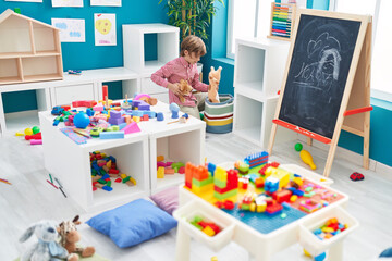 Sticker - Adorable caucasian boy holding dolls at kindergarten