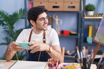 Sticker - Young hispanic man artist smiling confident listening to music at art studio