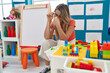 © Krakenimages.com - Young blonde woman teacher sitting on chair with stressed expression at kindergarten