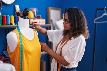 Sticker - Young hispanic woman tailor measuring t shirt at sewing studio