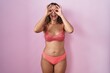 © Krakenimages.com - Young hispanic woman wearing lingerie over pink background doing ok gesture like binoculars sticking tongue out, eyes looking through fingers. crazy expression.
