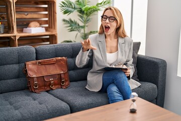 Canvas Print - Hispanic woman working at consultation office shouting and screaming loud to side with hand on mouth. communication concept.