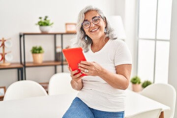 Poster - Middle age woman using touchpad sitting on table at home