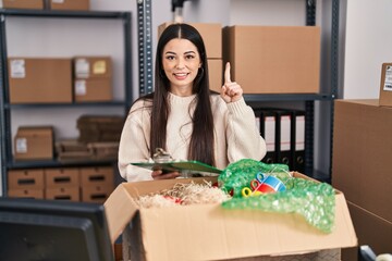 Canvas Print - Young woman working at small business ecommerce smiling with an idea or question pointing finger with happy face, number one