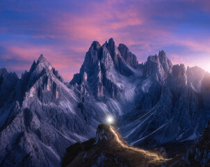 Wall Mural - Flashlight trails on mountain path against high rocks at night in summer. Tre cime, Dolomites, Italy. Colorful landscape with light trails, trail on the hill, mountain peaks, sky with pink clouds