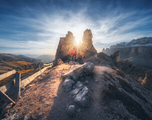 Wall Mural - Woman on the mountain trail and stones at sunset in spring in Dolomites, Italy. Sporty girl on the path and high rocks. Colorful landscape with cliffs, stones, blue sky. Trekking and hiking. Travel