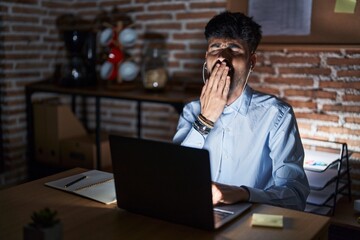 Canvas Print - Young hispanic man with beard working at the office at night bored yawning tired covering mouth with hand. restless and sleepiness.