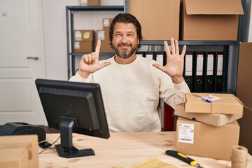 Sticker - Handsome middle age man working at small business ecommerce showing and pointing up with fingers number seven while smiling confident and happy.